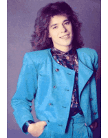 a young man with long hair wearing a blue suit