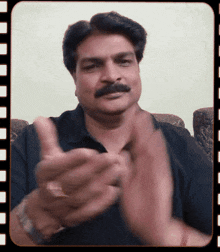a man with a mustache is clapping his hands while wearing a gold ring
