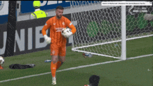 a soccer goalie is holding a ball in front of a banner that says unibet