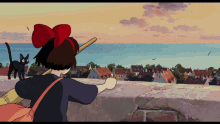 a girl with a red bow on her head is standing on a ledge with a black cat