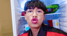 a man wearing glasses is making a funny face in a refrigerator .