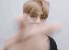 a man with blonde hair is making a peace sign with his hands .