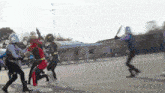 a group of people dressed in superhero costumes are fighting on a street