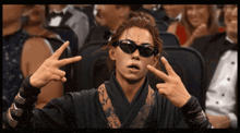 a man wearing sunglasses makes a peace sign with his hands