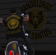 a man is riding a motorcycle in front of a banner that says bandoleros