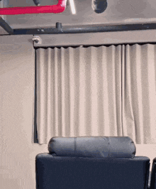 a black couch sits in front of a white curtain