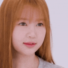 a close up of a young woman 's face with long red hair and bangs .