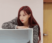 a woman with red hair is leaning on a white shelf
