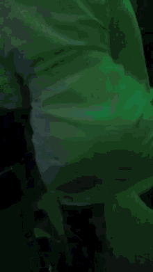a person is dancing in a dark room with a green light behind them .