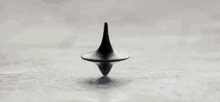 a black spinning top is floating in the air on a table .