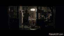 a woman is sweeping the floor in a dark kitchen in a movie scene .