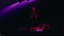 a man singing into a microphone on a stage with purple lights and the letter d below him