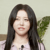 a woman with long black hair wearing a pink shirt and a microphone