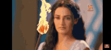 a woman in a white dress is holding a torch in her hand .