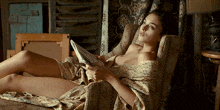 a woman is laying in a chair reading a magazine