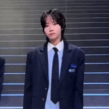 a young man wearing a suit and tie is standing in front of a set of stairs .