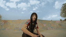 a girl in a red adidas shirt sits in front of a graffiti wall