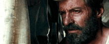 a close up of a man 's face with a beard looking out a window