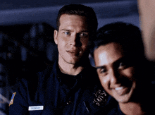 two police officers are standing next to each other in a dark room .