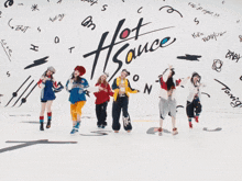 a group of young women are dancing in front of a wall that says hot sauce