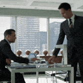 a man in a suit is standing next to another man in a suit and tie