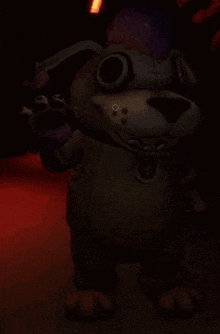 a stuffed animal is standing in a dark room holding a purple object .