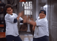 two men are dancing in a room with the words me written on the wall behind them .