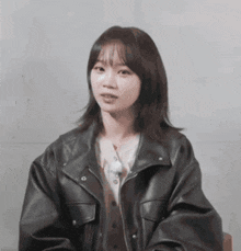 a woman wearing a black leather jacket and a white shirt