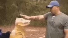 a man in a blue hat is petting a stuffed animal .