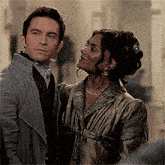 a man and a woman are standing next to each other in a room and looking at each other .