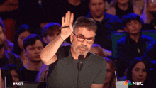 a man giving a high five in front of a crowd with a nbc logo in the background