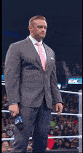 a man in a suit and tie is standing in a ring holding a microphone with the number 3 on it