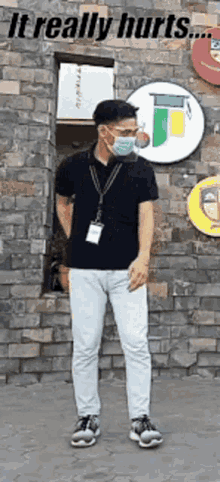 a man wearing a mask is standing in front of a brick wall ..