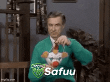 a man in a green sweater and tie is holding a stuffed clown in his hand .