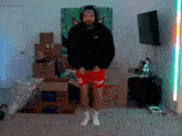 a man in a black hoodie and red shorts stands in front of a home depot box