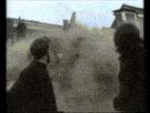 a man in a gas mask is standing next to another man in a gas mask in front of a plane .