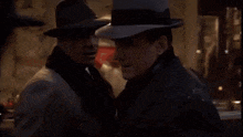 two men wearing hats are standing next to each other .
