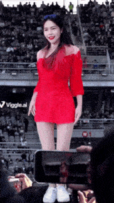 a woman in a red dress stands in front of a crowd and a sign that says viggle.ai