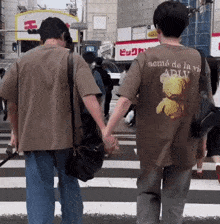 a man wearing a shirt that says neme de la vi is holding a woman 's hand