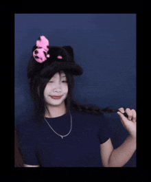 a young girl wearing a black hat with a pink bow