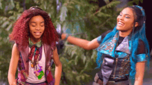 a couple of girls with red hair and blue hair are standing next to each other .