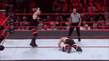 two men are wrestling in a wrestling ring with a referee standing behind them .
