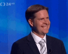 a man in a suit and tie is smiling on a television show .