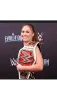 a woman is holding a wrestling championship belt and smiling