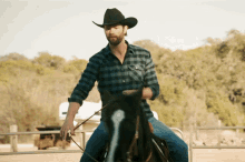 a man in a cowboy hat rides a black horse
