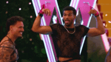 two men are standing next to each other in front of a pink sign .