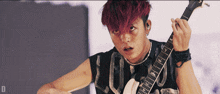 a man with red hair is holding a guitar with the letter d visible