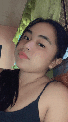 a woman wearing a black tank top is taking a selfie