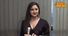 a woman holding a microphone with the words films of india behind her