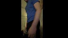 a man in a blue shirt and black pants stands in a room